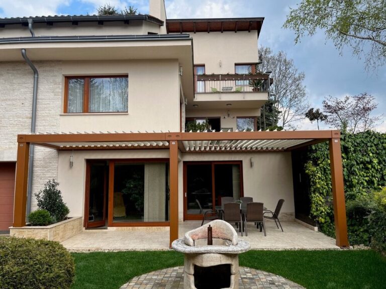 pergola bioclimatica din aluminiu maro efect de lemn atasata de casa